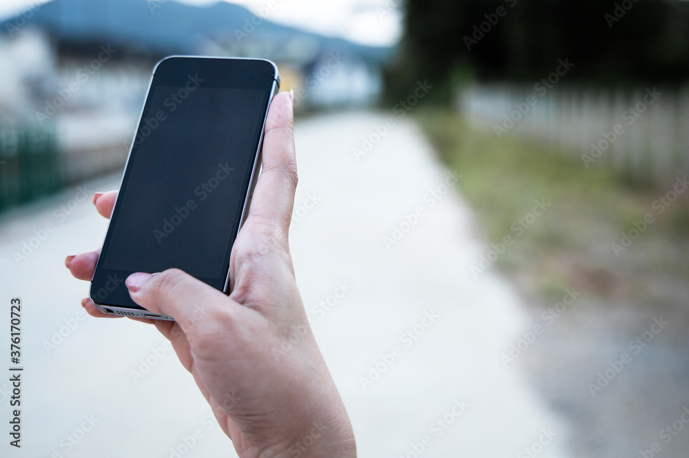 woman holding a smartphone with a blank black screen and empty space, technological ideas and text space.
