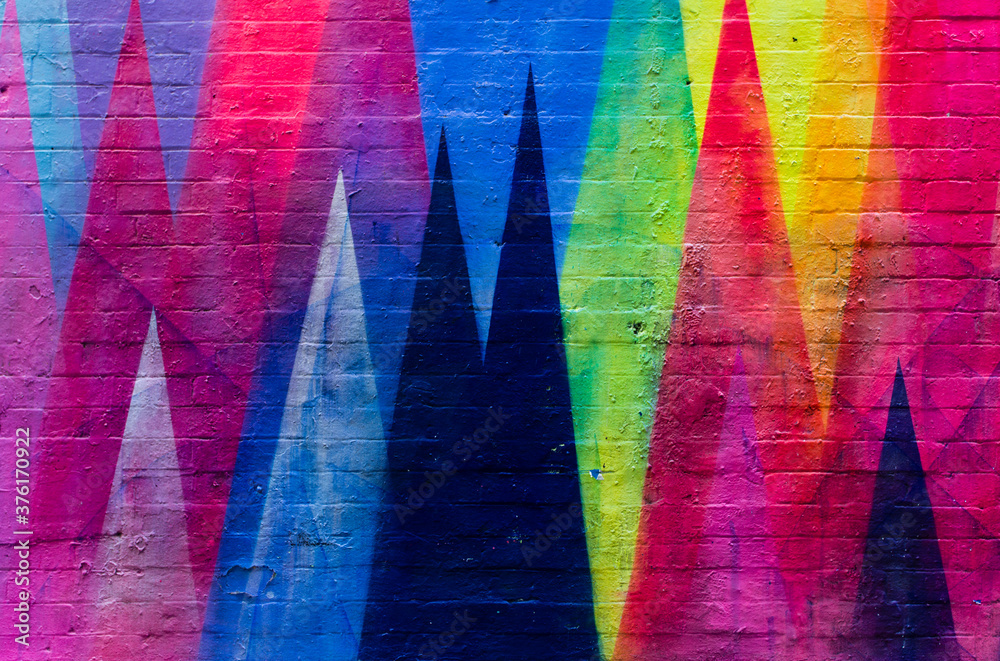 Brick wall painted in vibrant colors with geometric figures - obrazy, fototapety, plakaty 