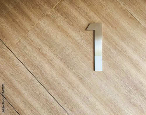 Number one on parquet floor as background, number concept on wooden background.