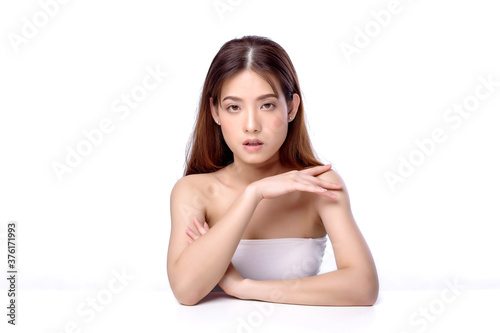  Portrait of beautiful charming young Asian woman posing facial and sitting with white table, beauty of female face with skincare on white background, healthcare and skin care concept.