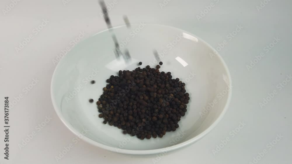Close up pouring black pepper corn into white bowl. Cooking concept Close up pouring black pepper corn into white bowl. Cooking concept
