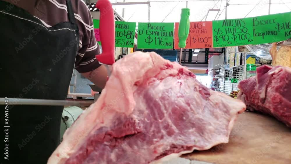 Carnicero con cubrebocas cortando la carne en el mercado 