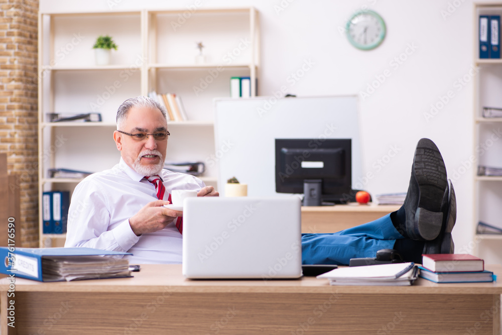 Old male employee enjoying coffee during coffee break
