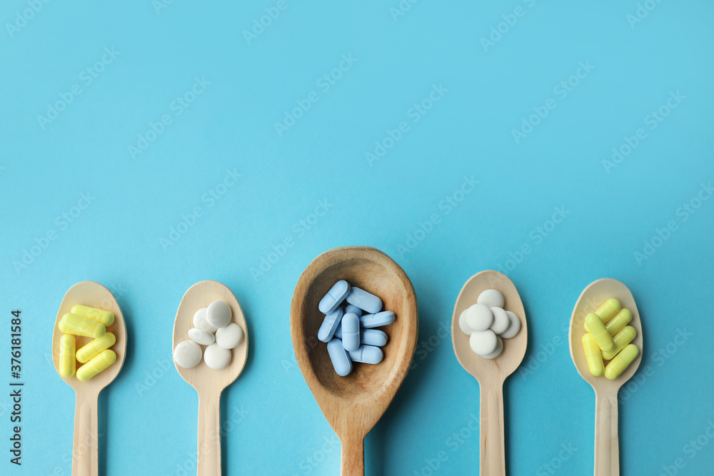 multi-colored tablets in wooden spoons are placed at the bottom of the banner. blue background. banner with place for text in the middle multi-colored tablets in wooden spoons are placed at the bottom of the banner. blue background. banner with place for text in the middle
