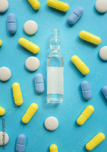 Various pills and ampoule on a blue background.