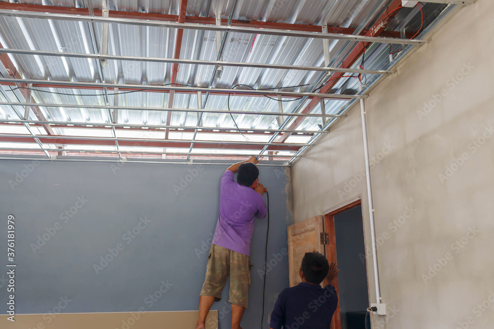 Fototapeta premium Construction workers install the ceiling