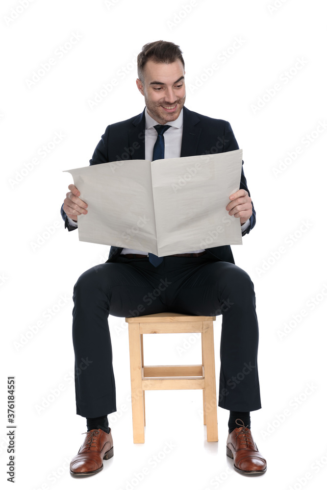Positive businessman reading newspaper and smiling Positive businessman reading newspaper and smiling