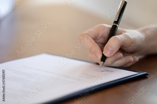 Close up woman holding pen, signing document, client customer making medical insurance or purchasing deal, putting signature on agreement after successful negotiations with lawyer, advisor, realtor