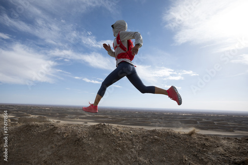 Fitness woman trail runner cross country running on sand desert dunes