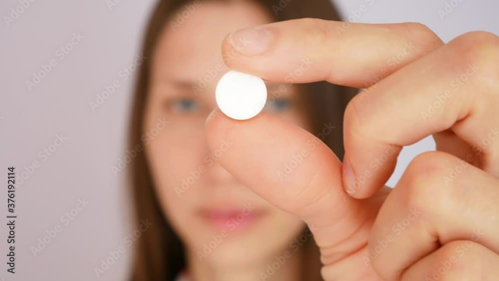 A young handsome woman takes medicine in a pill form A young handsome woman takes medicine in a pill form