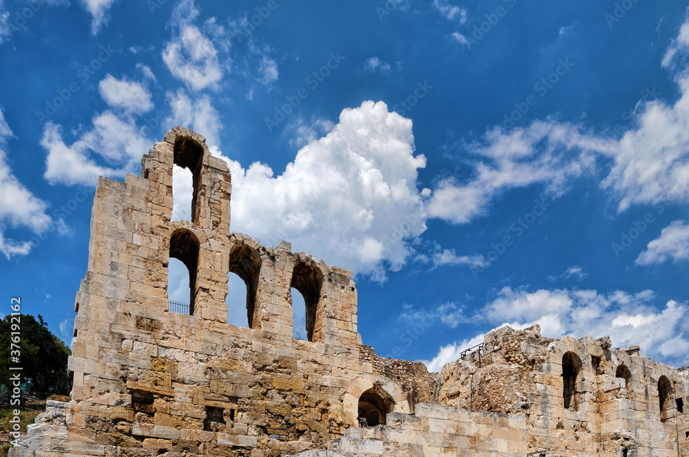 View of Odeon of Herodes Atticus theater on Acropolis hill, Athens, Greece, against bright blue sky and super clouds. UNESCO world heritage