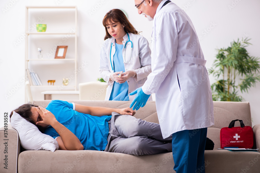 Two doctors visiting sick young man at home Two doctors visiting sick young man at home
