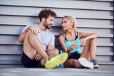 Modern urban couple making pause on the sidewalk during jogging / exercise.