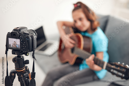 Child guitarist making video lessons and tutorials for internet vlog website classes.