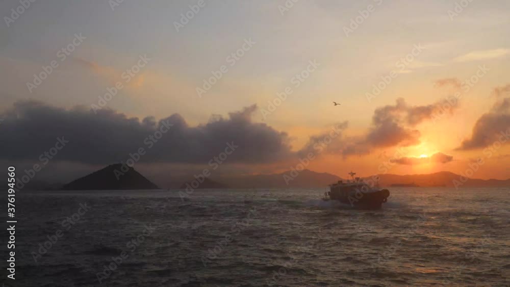 time lapse of Hong Kong Boats to Macau and other Outlying Islands at Sunset at Water front at Western District Public Cargo Working Area, Victoria Harbour, Hong Kong. Green island in distance time lapse of Hong Kong Boats to Macau and other Outlying Islands at Sunset at Water front at Western District Public Cargo Working Area, Victoria Harbour, Hong Kong. Green island in distance