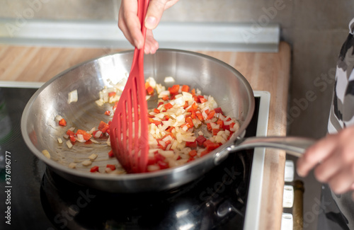 fried peppers and onions in a preheated pan, preparing a meal at home