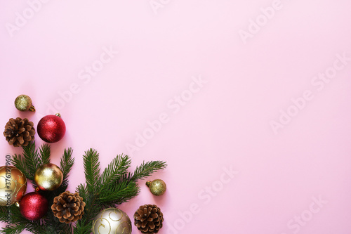Beautiful Christmas composition on a red background with fir. Pink background with fir, christmas balls and decor. Top view with space for copy.