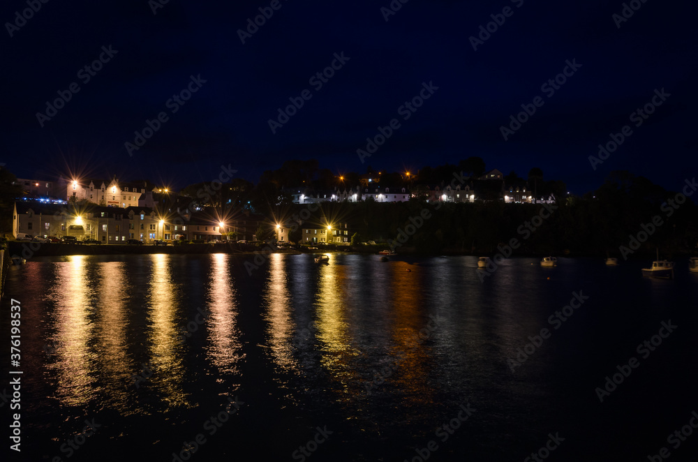 City landscape,of Portree at night with the lights of lamppost reflected on the sea water, Isle of Skye, United Kingdom