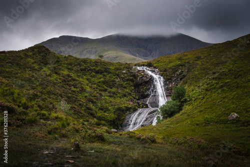 A nature landscape with a waterfall under a cloudy sky in the Isle of Skye, Scotland, United Kingdom