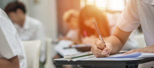 Exam at school with student's taking educational admission test in class, thinking hard, writing answer in university classroom, education and world literacy day concept