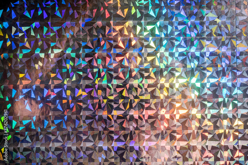 macro photo of silver rainbow holographic foil, colorful hologram surface, glitter grid pattern background. photo