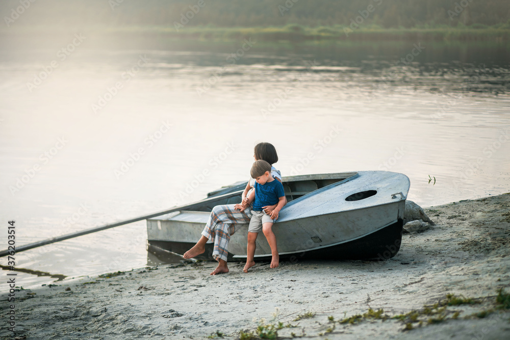 Naklejka premium children are sitting on a boat near the lake on the shore and soft sunlight is shining on them