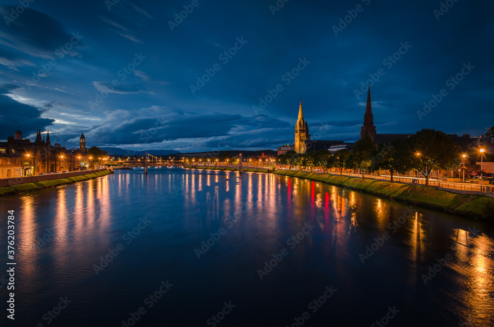 Inverness city landscape at night with the lights reflected in the river Ness, Scotland, United Kingdom