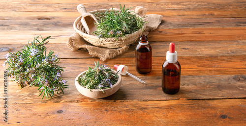 two Bottles of rosemary essential oil on a wooden table