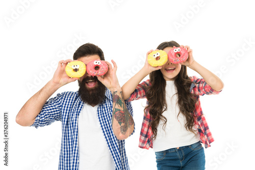 Funny dessert glasses. Father and small girl child smiling with donut dessert on eyes. Bearded man and little daughter having fun with dessert food. Happy family enjoying dessert course together