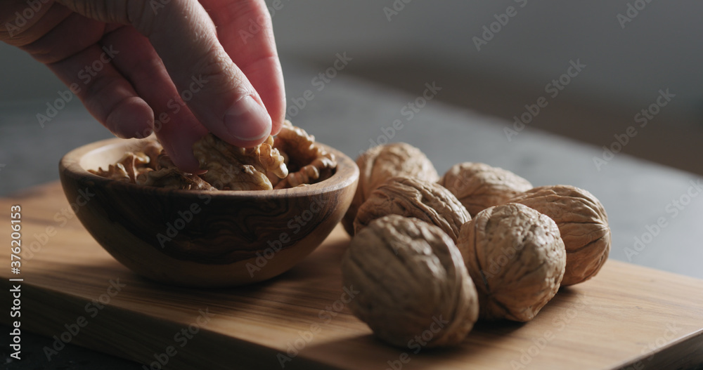 man hand take walnut kernels from wooden bowl man hand take walnut kernels from wooden bowl