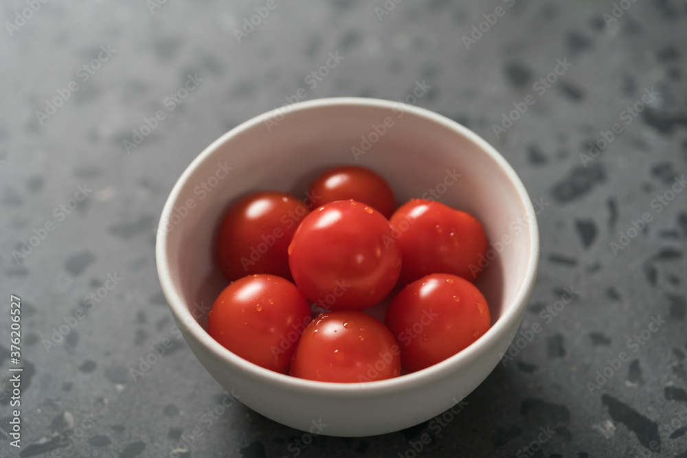 ripe cherry tomatoes in white bowl on concrete surface ripe cherry tomatoes in white bowl on concrete surface