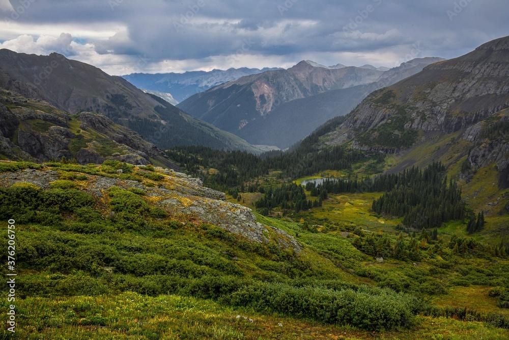 Mountain pass in the summer with green grass and storm clouds during a hike in colorado