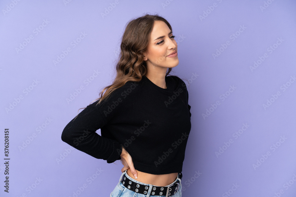 Young woman over isolated purple background suffering from backache for having made an effort
