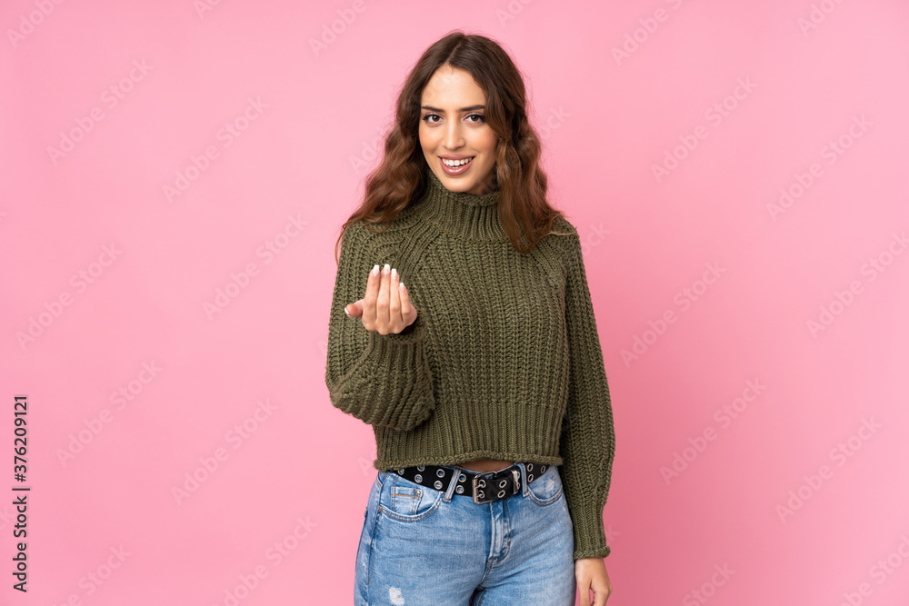 Young woman over isolated pink background inviting to come with hand. Happy that you came Young woman over isolated pink background inviting to come with hand. Happy that you came