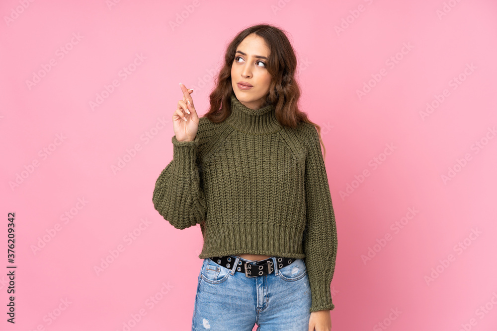Young woman over isolated pink background with fingers crossing and wishing the best Young woman over isolated pink background with fingers crossing and wishing the best