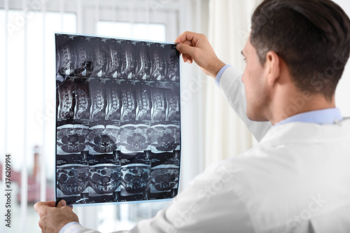 Orthopedist examining X-ray picture near window in office