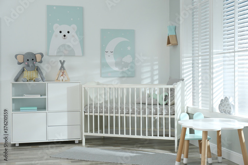 Stylish baby room interior with crib and cute pictures on wall