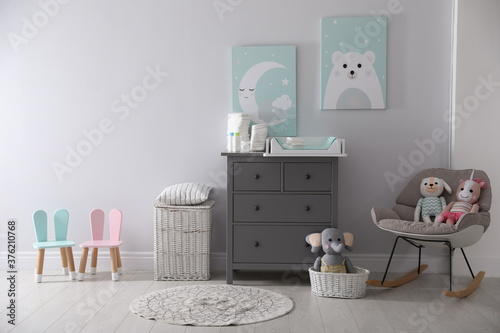 Chest of drawers with changing tray and pad in baby room. Interior design photo