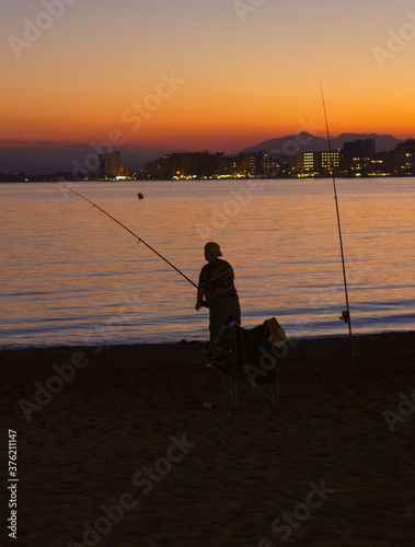 silhouette of a man fishing in the sea with a sunset