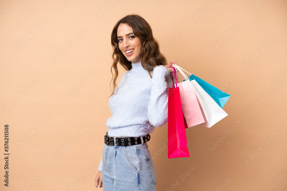 Young woman over isolated background holding shopping bags and smiling