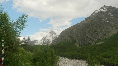 View of green mountain valley and woman walking among trees. Hiking as tourism. photo