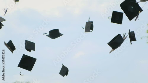 Close up in slow motion of university high school graduates throwing their square academic Tudor bonnet cap into the air graduation ceremony. Students Celebration of a MBA bachelor and master degree photo