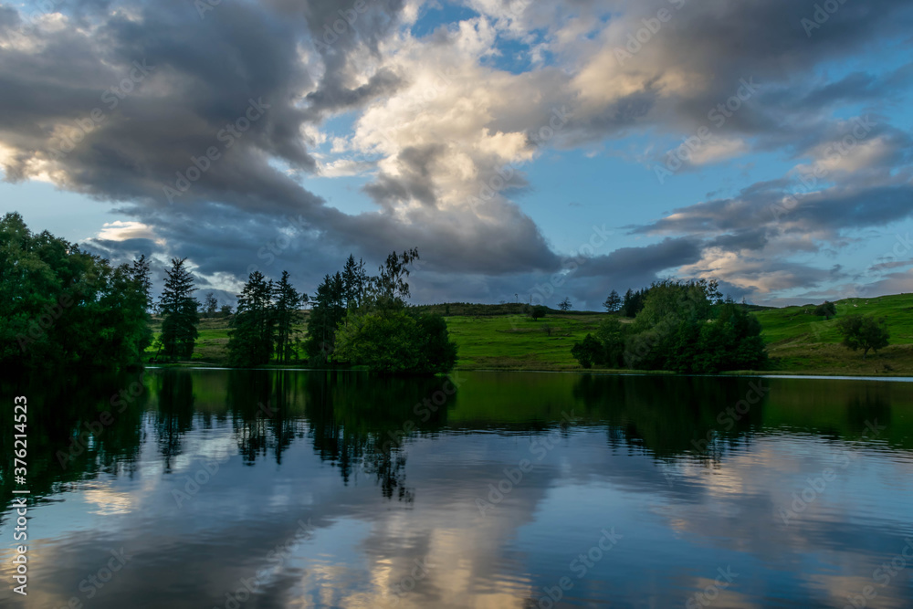 Beautiful cloudy sky has reflection in forest lake during sunset Beautiful cloudy sky has reflection in forest lake during sunset