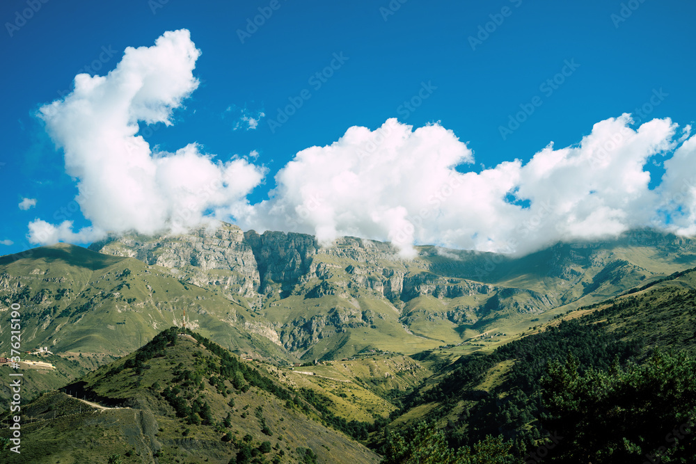 Picturesque scenery. Mountain against cloudy sky. Clouds floating on blue sky over mountain ridge.