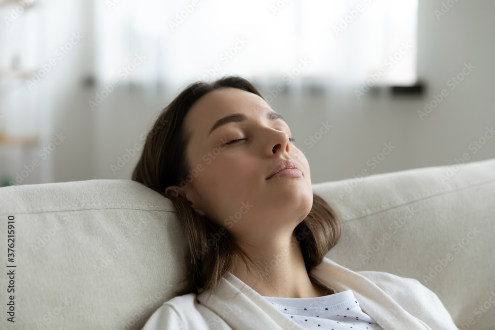 Close up head shot tired millennial woman leaning on cozy couch, enjoying lazy stress free weekend time at home. Tranquil peaceful young girl napping with closed eyes on sofa, daydreaming indoors. Close up head shot tired millennial woman leaning on cozy couch, enjoying lazy stress free weekend time at home. Tranquil peaceful young girl napping with closed eyes on sofa, daydreaming indoors.