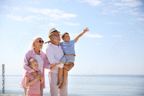 Happy grandparents with little children on sea beach