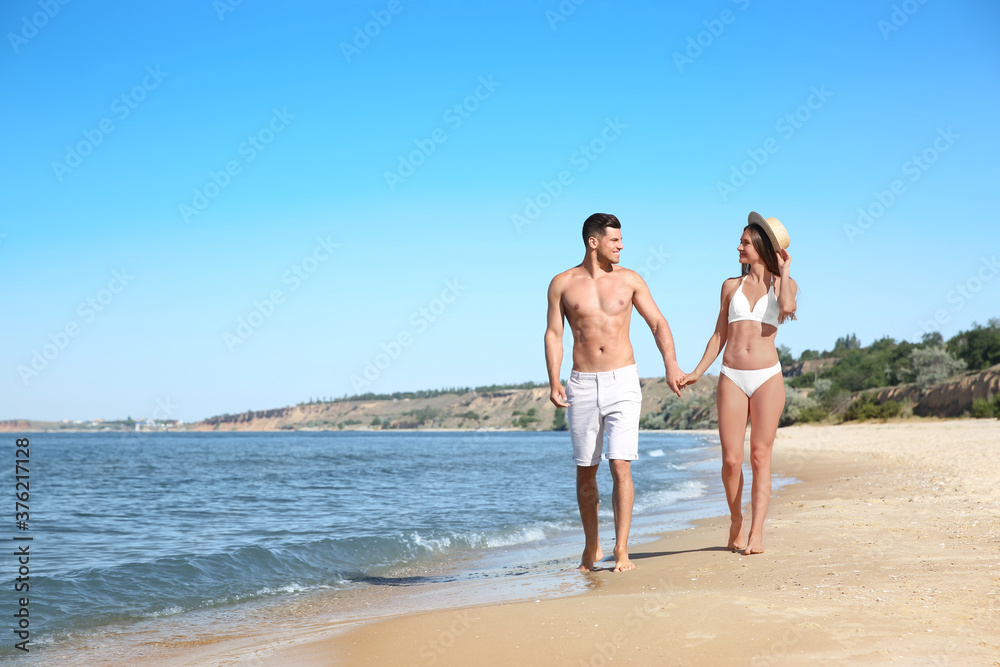 Woman in bikini and her boyfriend on beach, space for text. Happy couple