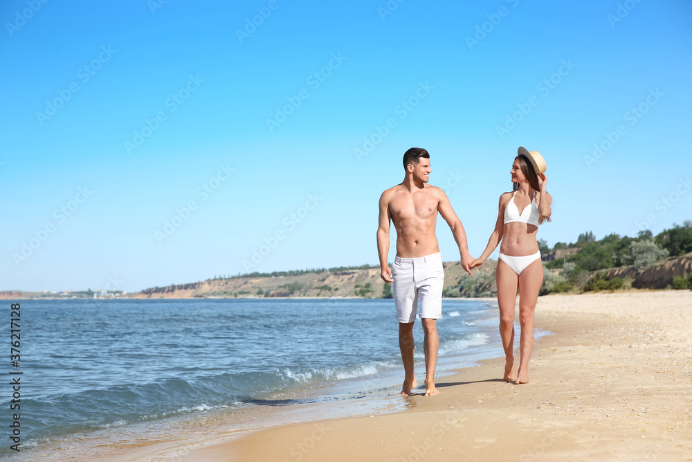 Woman in bikini and her boyfriend on beach, space for text. Happy couple Woman in bikini and her boyfriend on beach, space for text. Happy couple