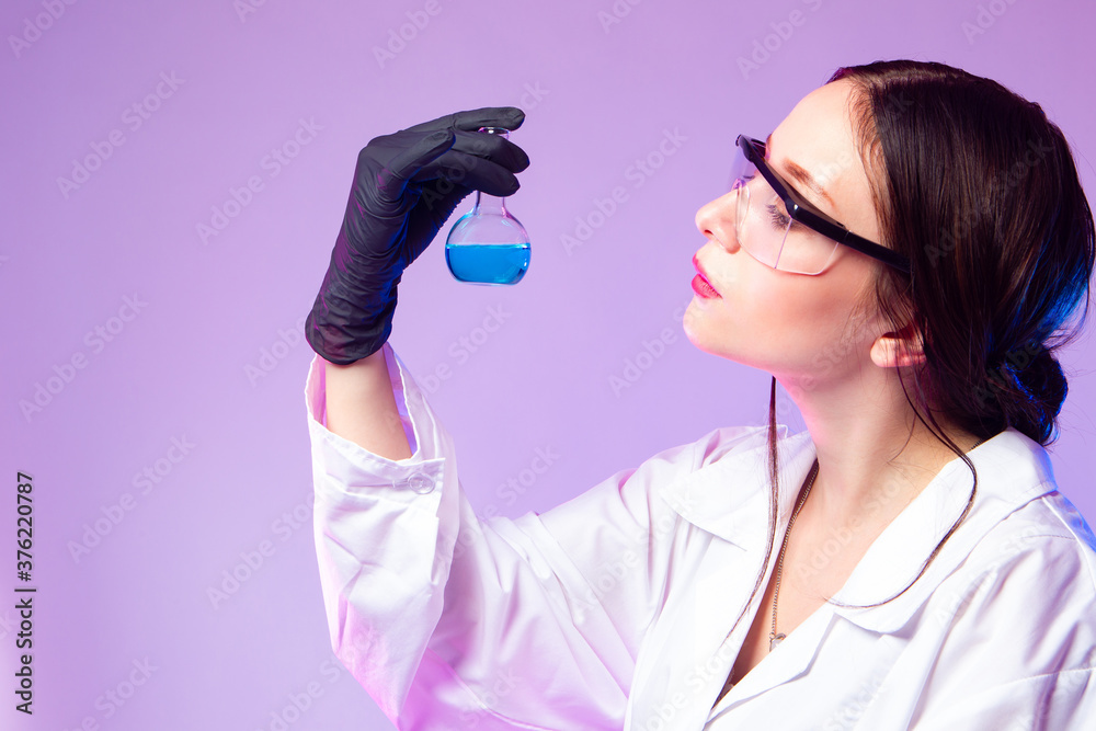 Portrait of a female chemist in profile. The girl holds a test tube with a blue chemical liquid. Concept of chemical research with space for text. Results of a laboratory experiment. Portrait of a female chemist in profile. The girl holds a test tube with a blue chemical liquid. Concept of chemical research with space for text. Results of a laboratory experiment.
