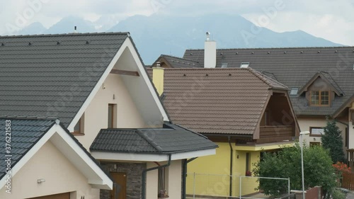 Changing focus from cup to montains. Close up woman holding a white cup on the balcony with amaying view on modern houses or pensions and high mountains. photo